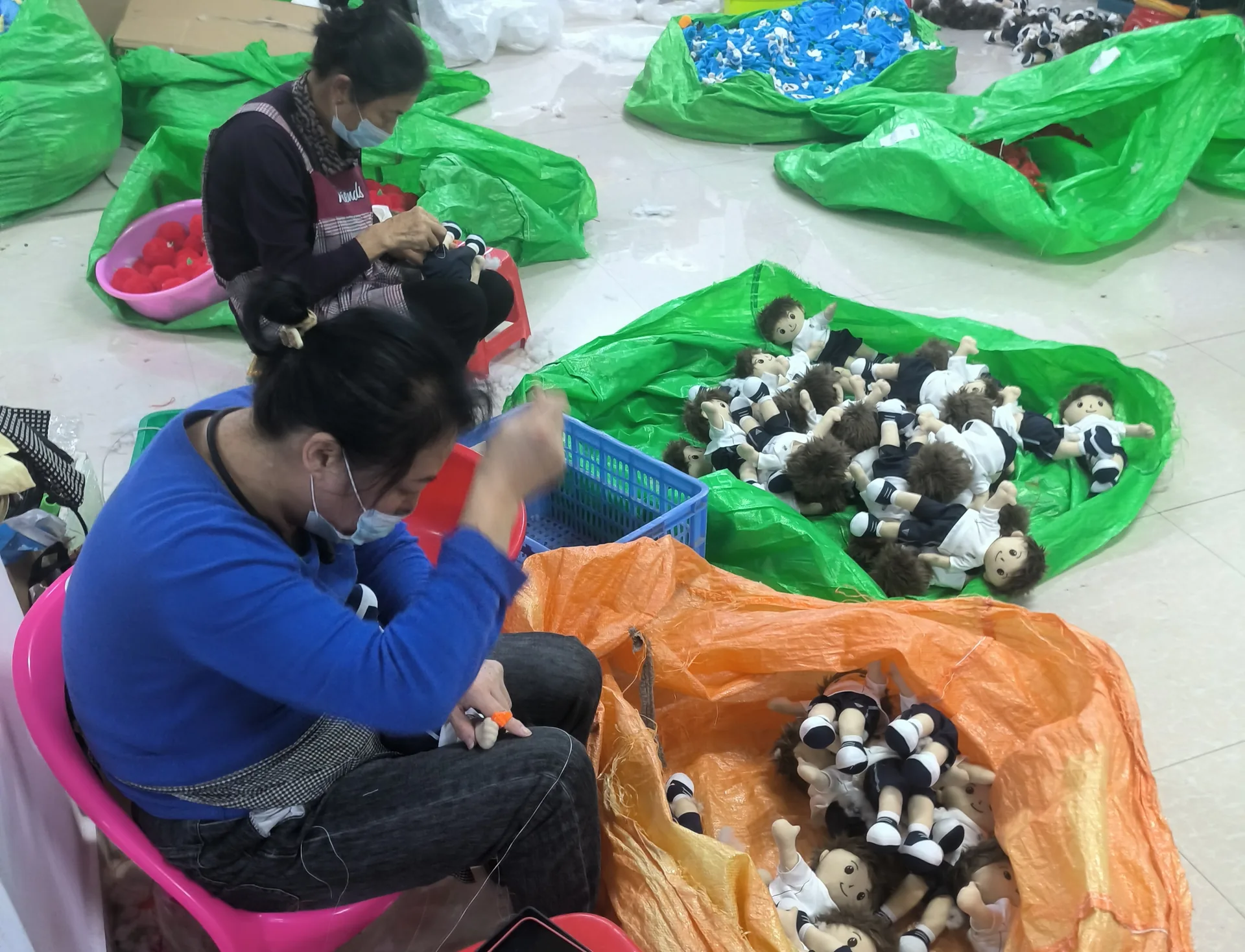 Workers assembling plush toys at a production table